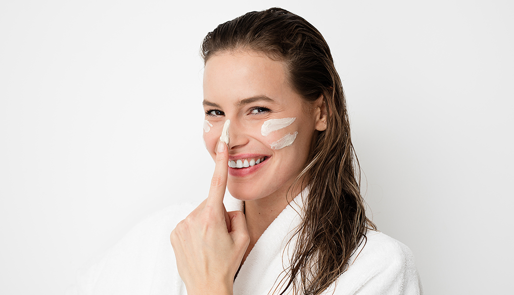Cuidado facial, mujer joven aplicándose crema en el rostro para el post mejor rutina de cuidado facial