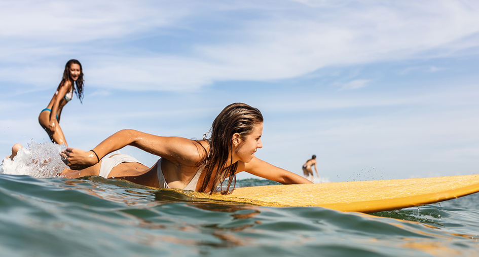 Chicas surfeando para el post 4 consejos sobre protección solar para no quemarte este verano