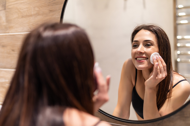 Mujer peeling facial frente al espejo